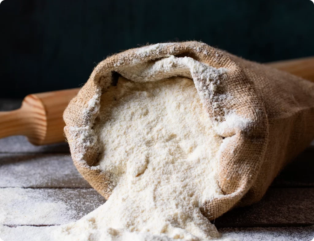 sacco di farina appoggiato ad una superficie di legno con un mattarello